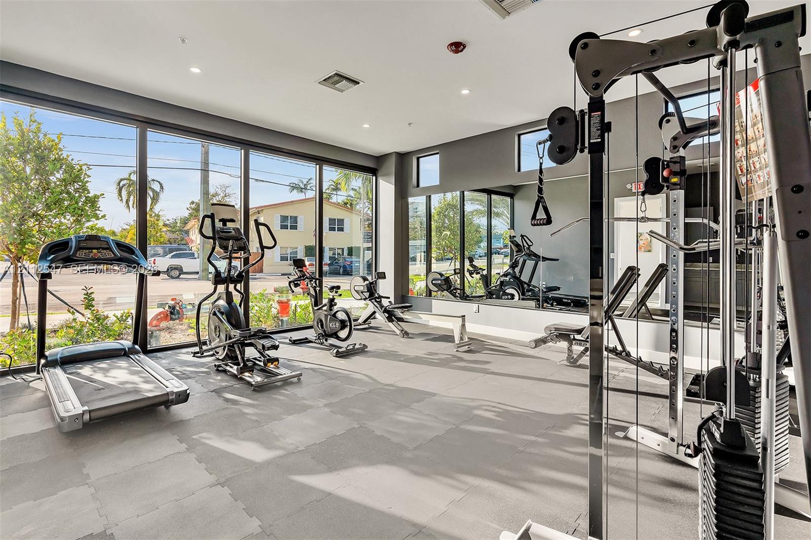 Fitness center featuring floor-to-ceiling windows, full-wall mirrors, recessed lighting, and rubberized modular flooring