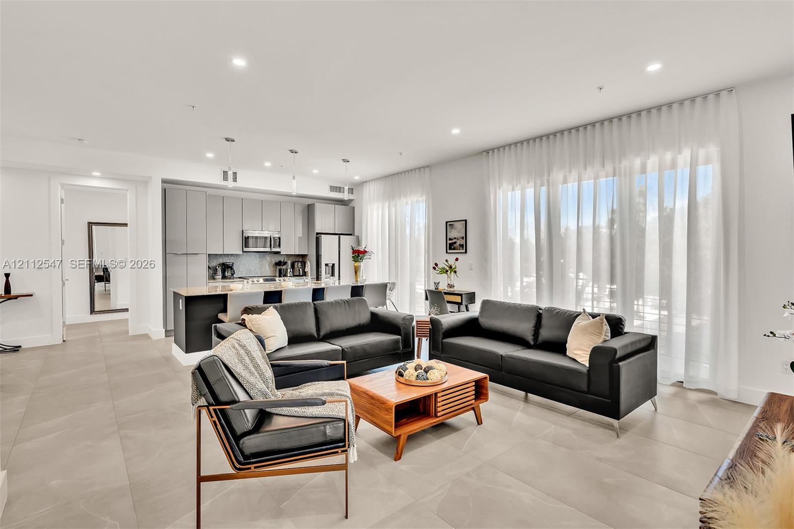 Open-concept interior featuring large-format tile flooring, recessed lighting, and expansive floor-to-ceiling windows