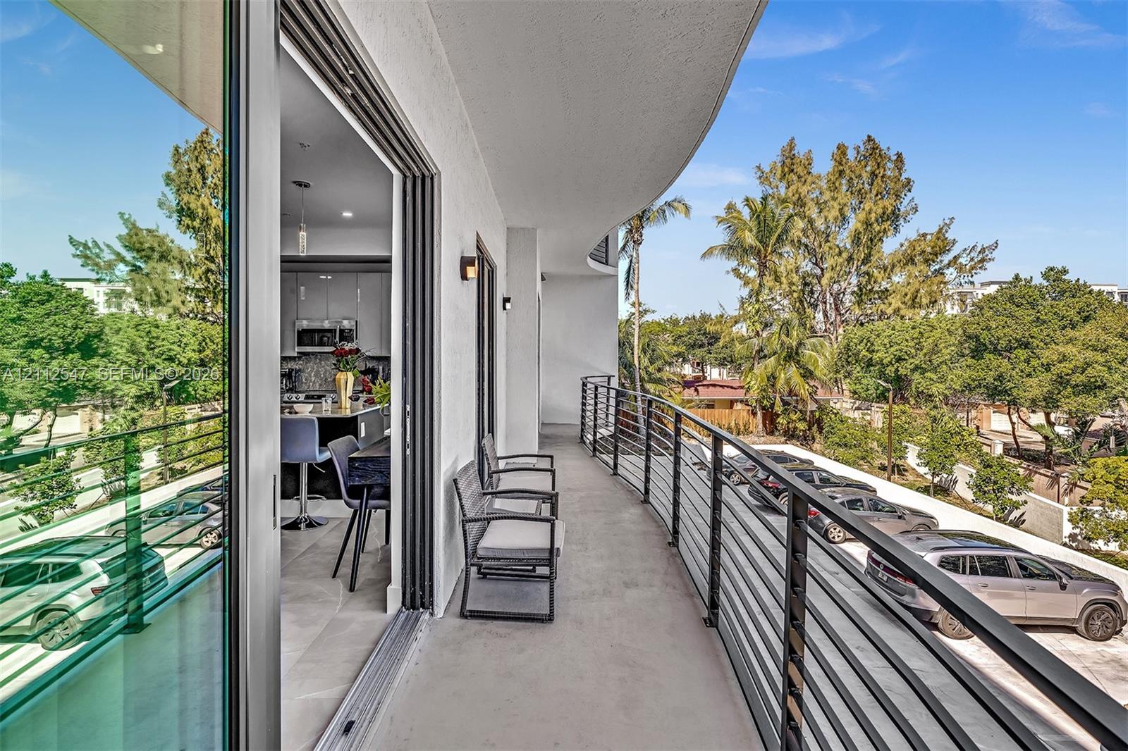 Covered balcony featuring a concrete floor, minimalist black metal railing, and floor-to-ceiling sliding glass doors