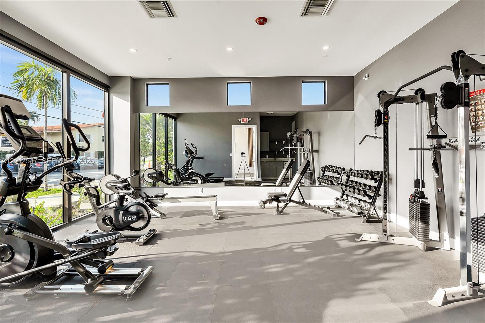 Fitness room featuring floor-to-ceiling windows, full-wall mirrors, recessed lighting, and resilient flooring