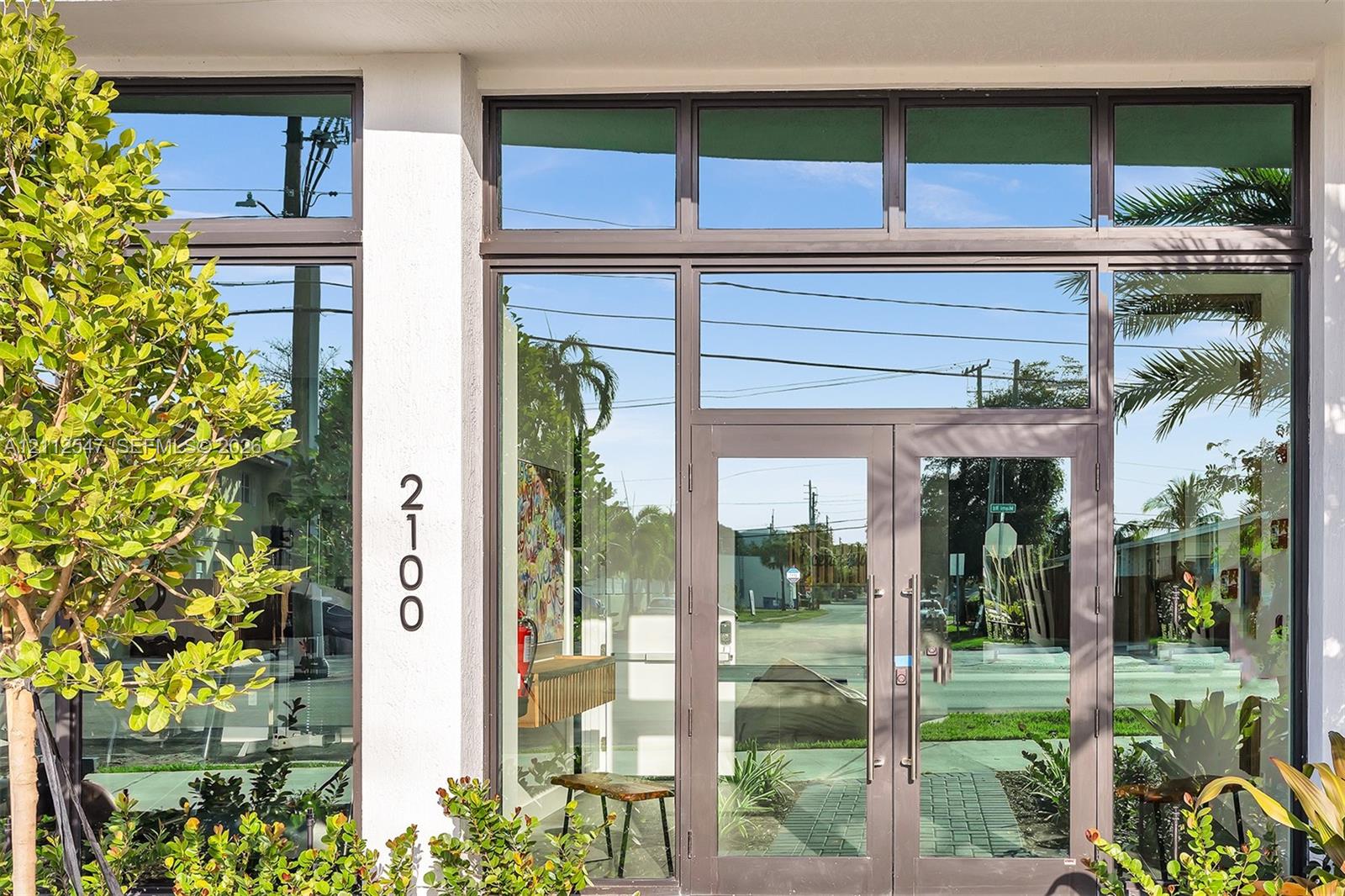 Entrance featuring a double-glass door entry, expansive floor-to-ceiling windows, dark-finished metal framing, and clerestory window accents