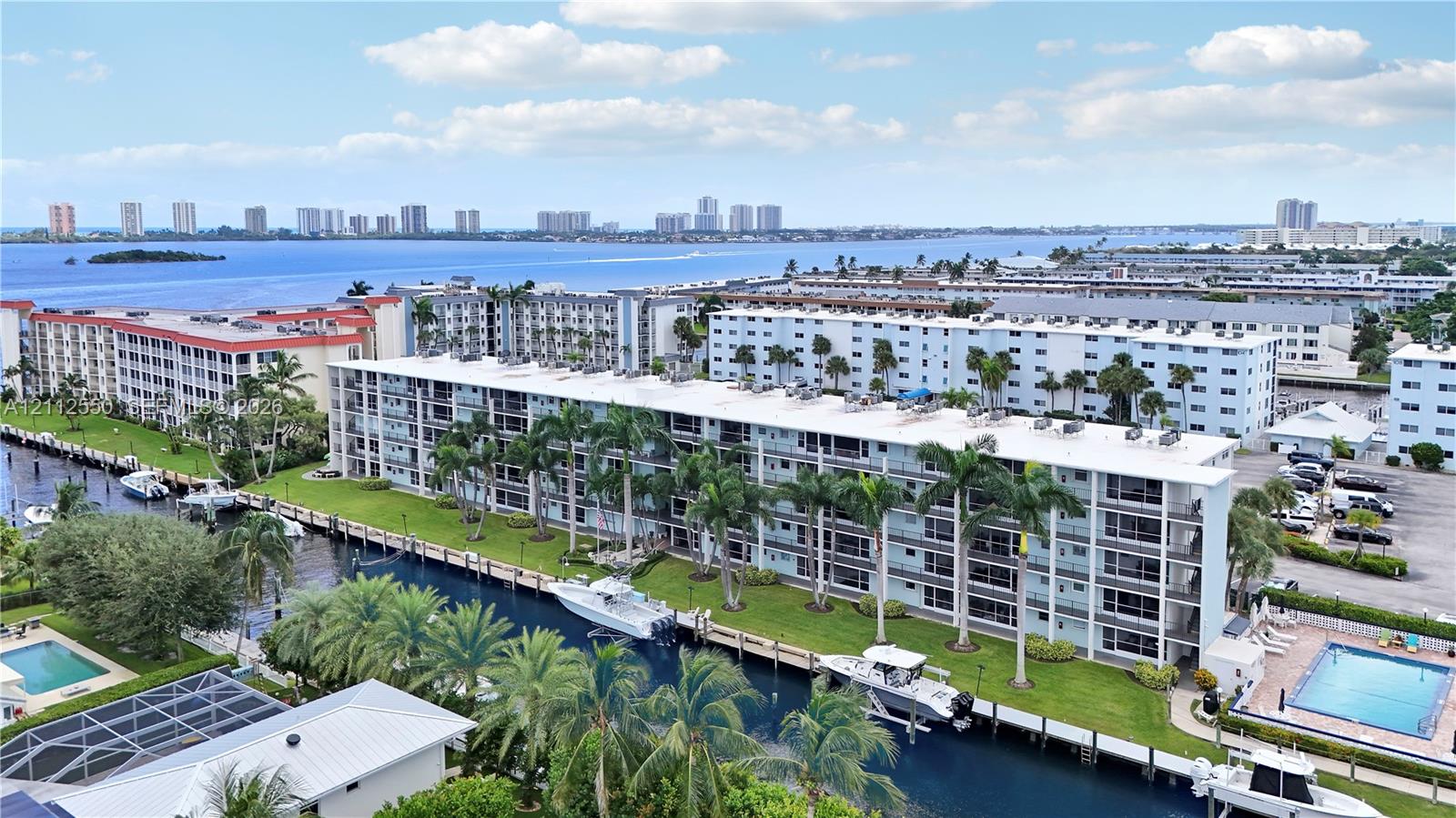 Waterfront residential complex featuring private boat slips, manicured grounds with palm trees, and two outdoor swimming pools