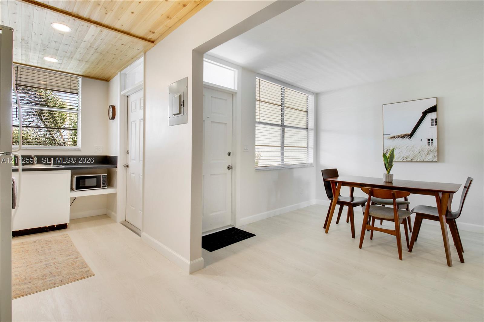 Bright interior space featuring light-toned wood-finish flooring, a vaulted natural wood-plank ceiling, recessed lighting, and large windows with horizontal blinds