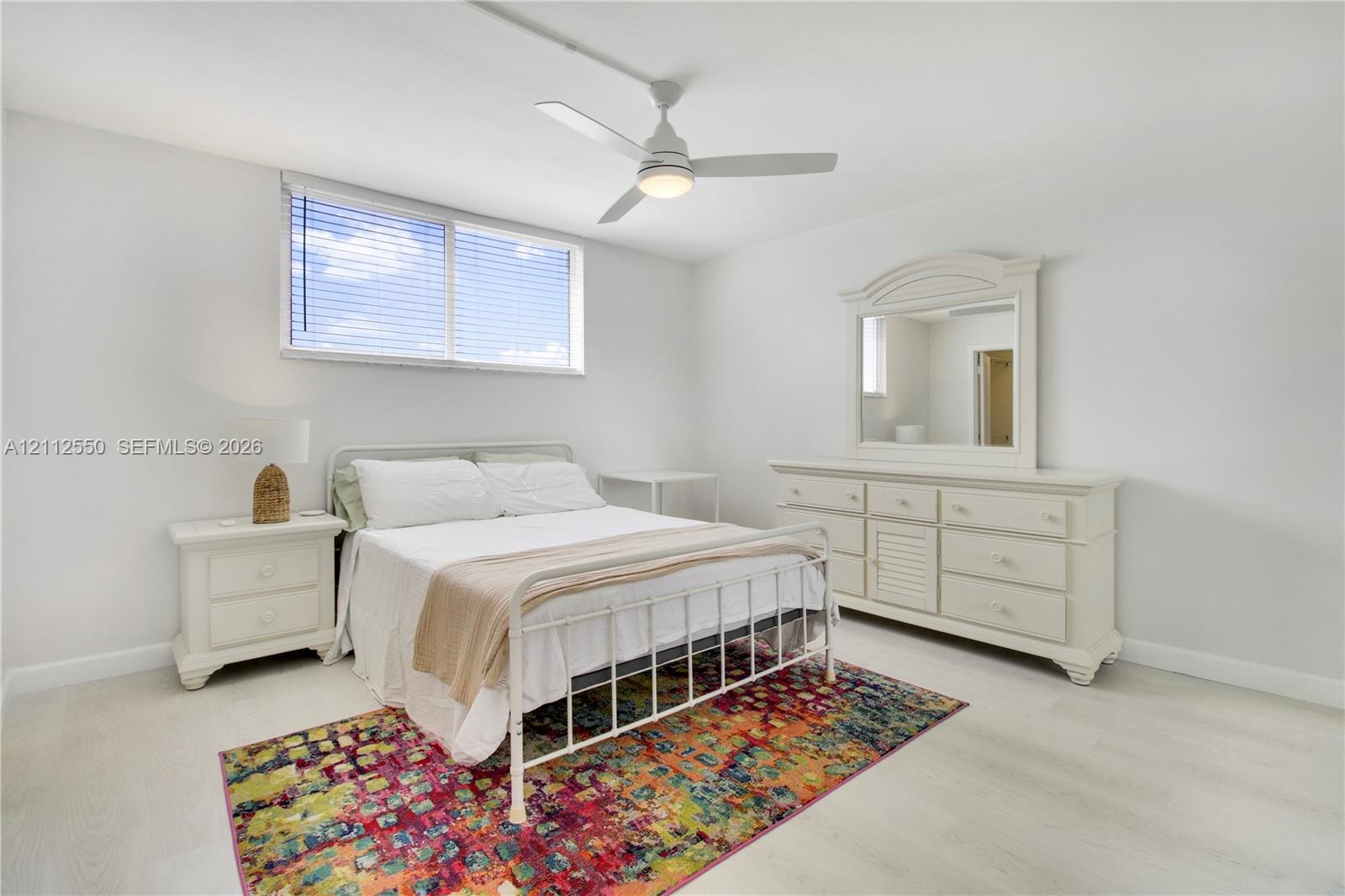 Neutral interior featuring wood-finish flooring, a contemporary ceiling fan with integrated lighting, and a window with horizontal blinds