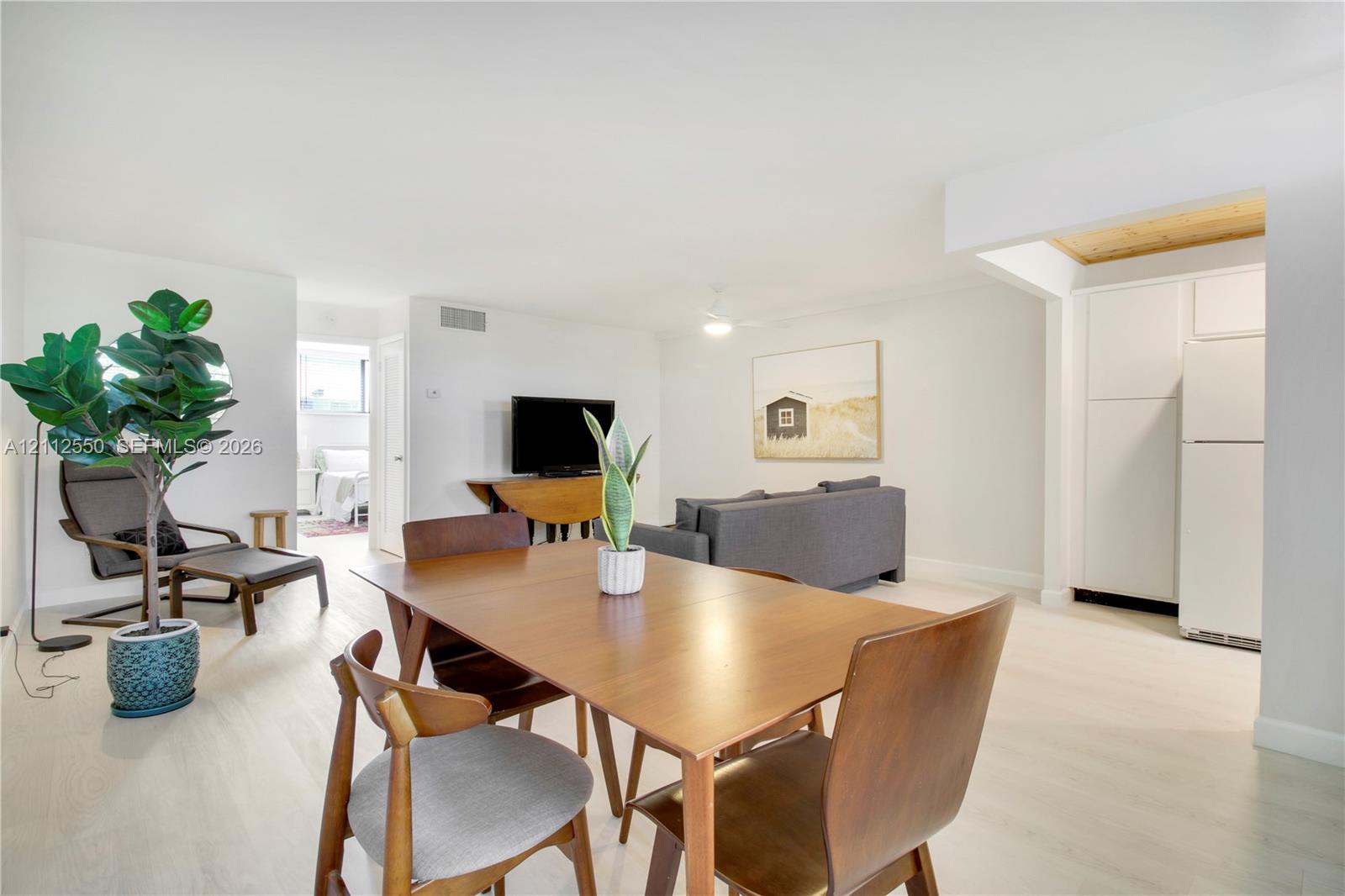 Open-concept interior featuring wood-finish flooring, ceiling fan, and built-in white cabinetry
