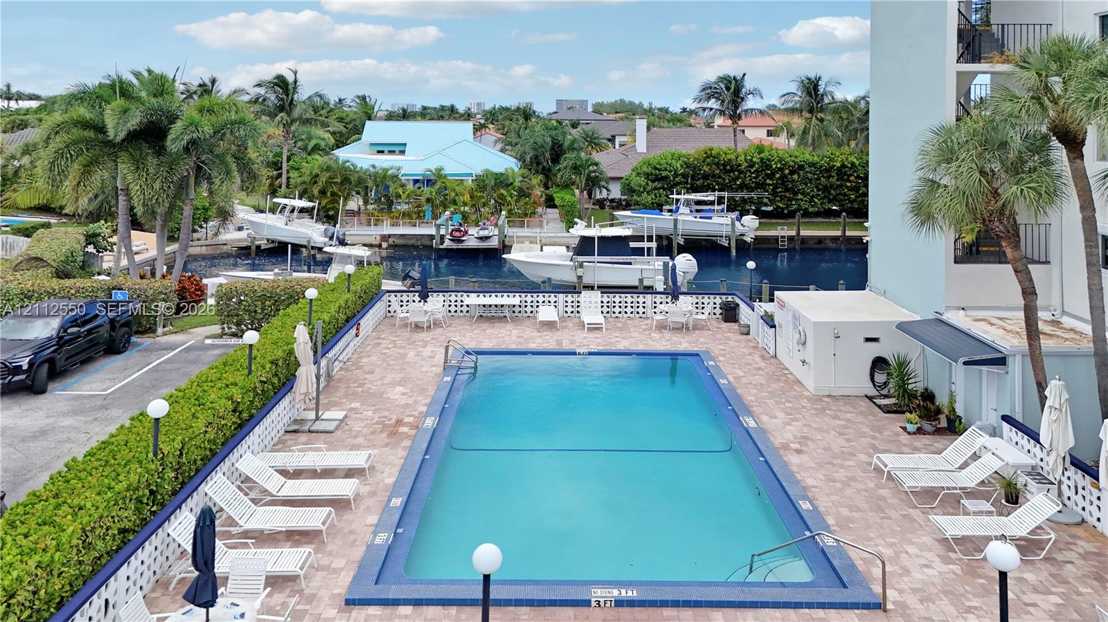 Swimming pool featuring a paved deck, perimeter hedge landscaping, and water access with boat slips