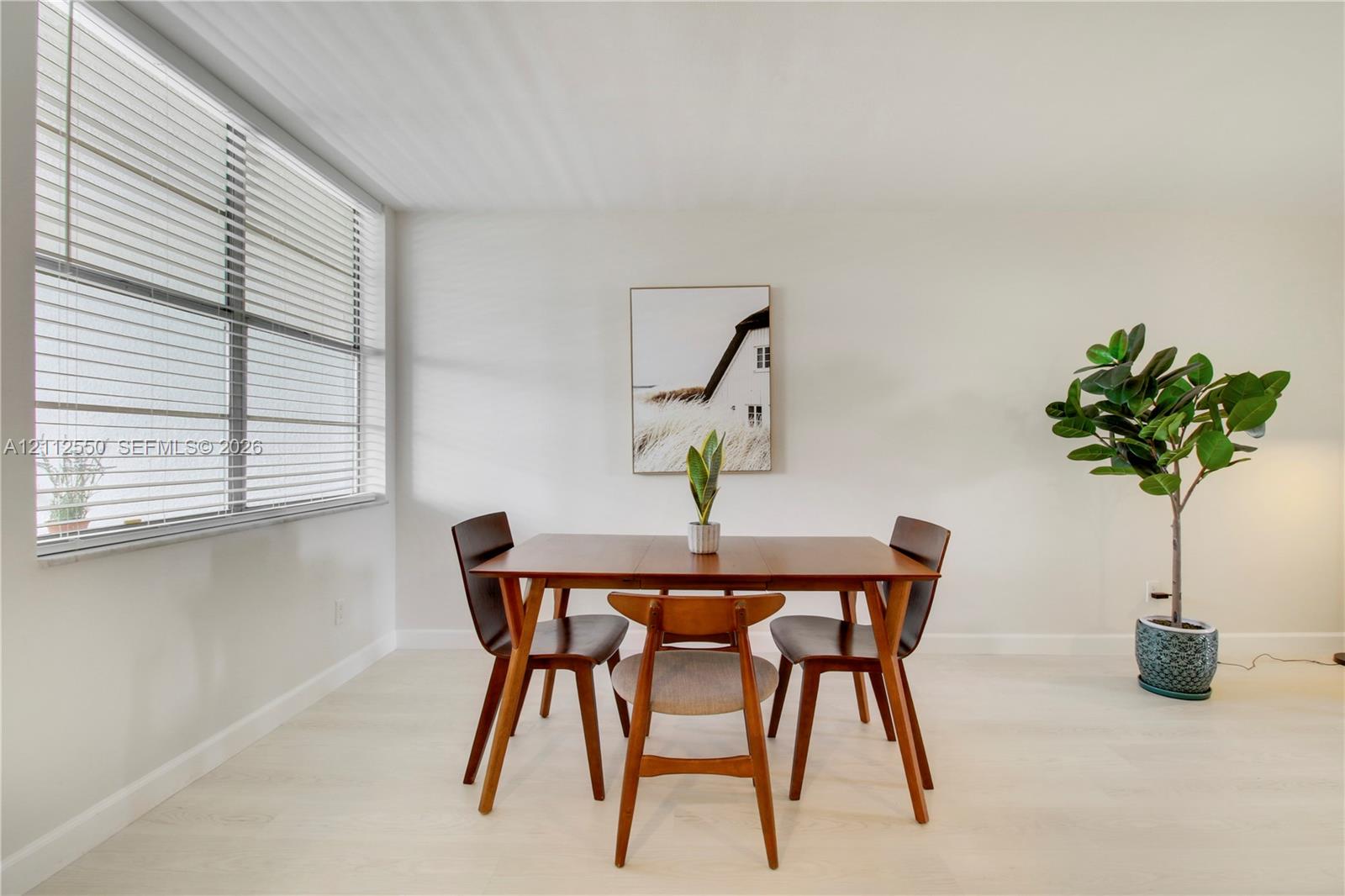 Neutral wall palette with wood-finish flooring and large-scale window featuring adjustable horizontal blinds