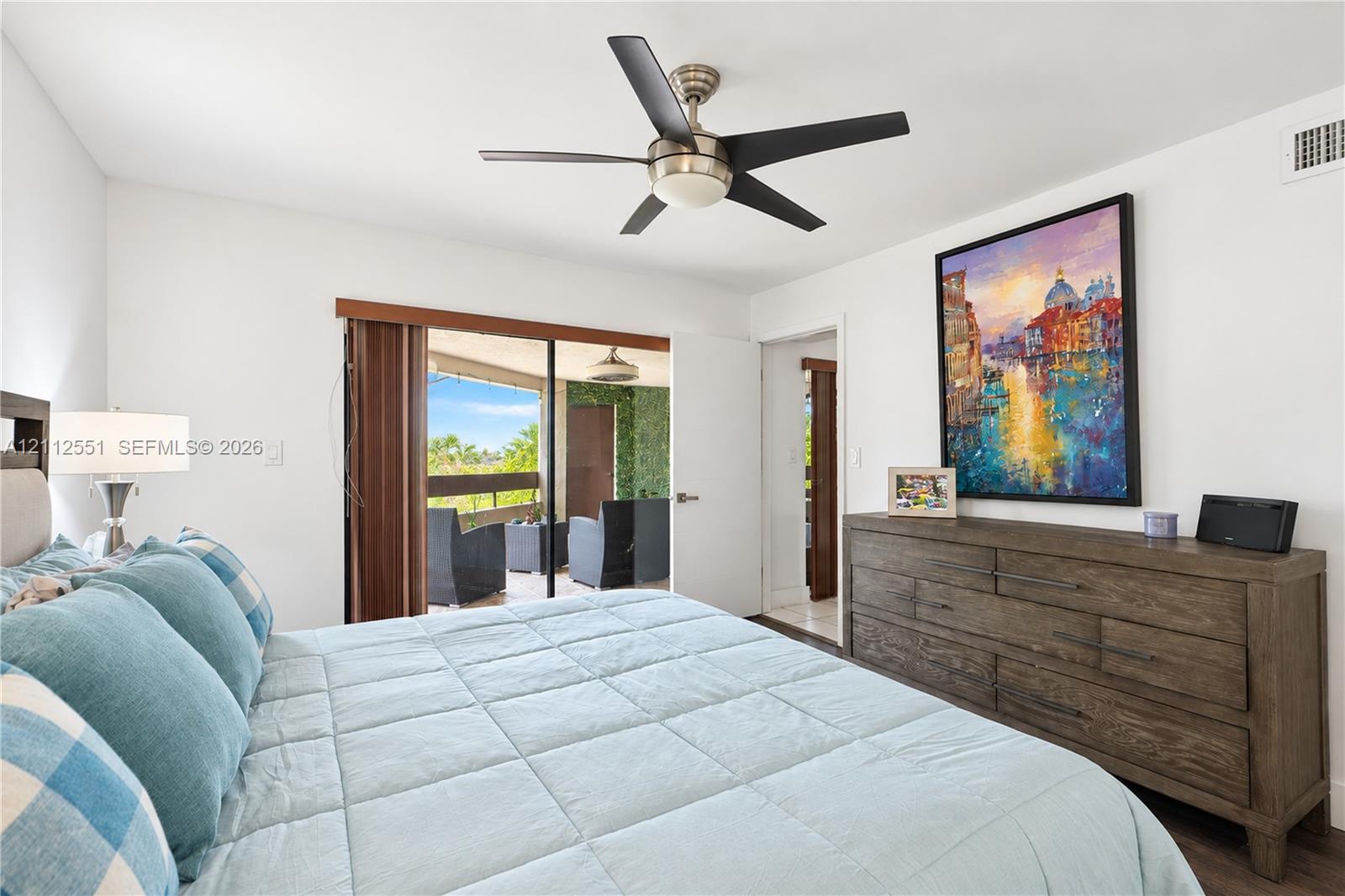 Spacious room featuring a brushed nickel ceiling fan with integrated lighting, wood-finish flooring, and sliding glass doors providing outdoor access