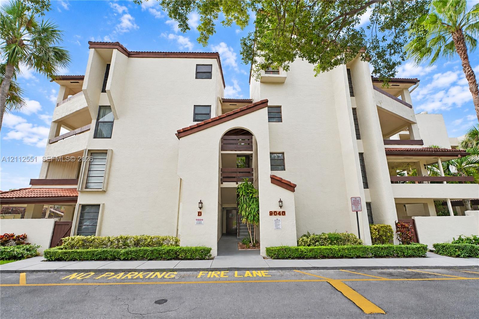 Multi-story stucco exterior featuring arched entryway detailing, tiled roof accents, integrated private balconies, and manicured landscaping Multi-story stucco exterior featuring arched entryway detailing, tiled roof accents, integrated private balconies, and manicured landscaping