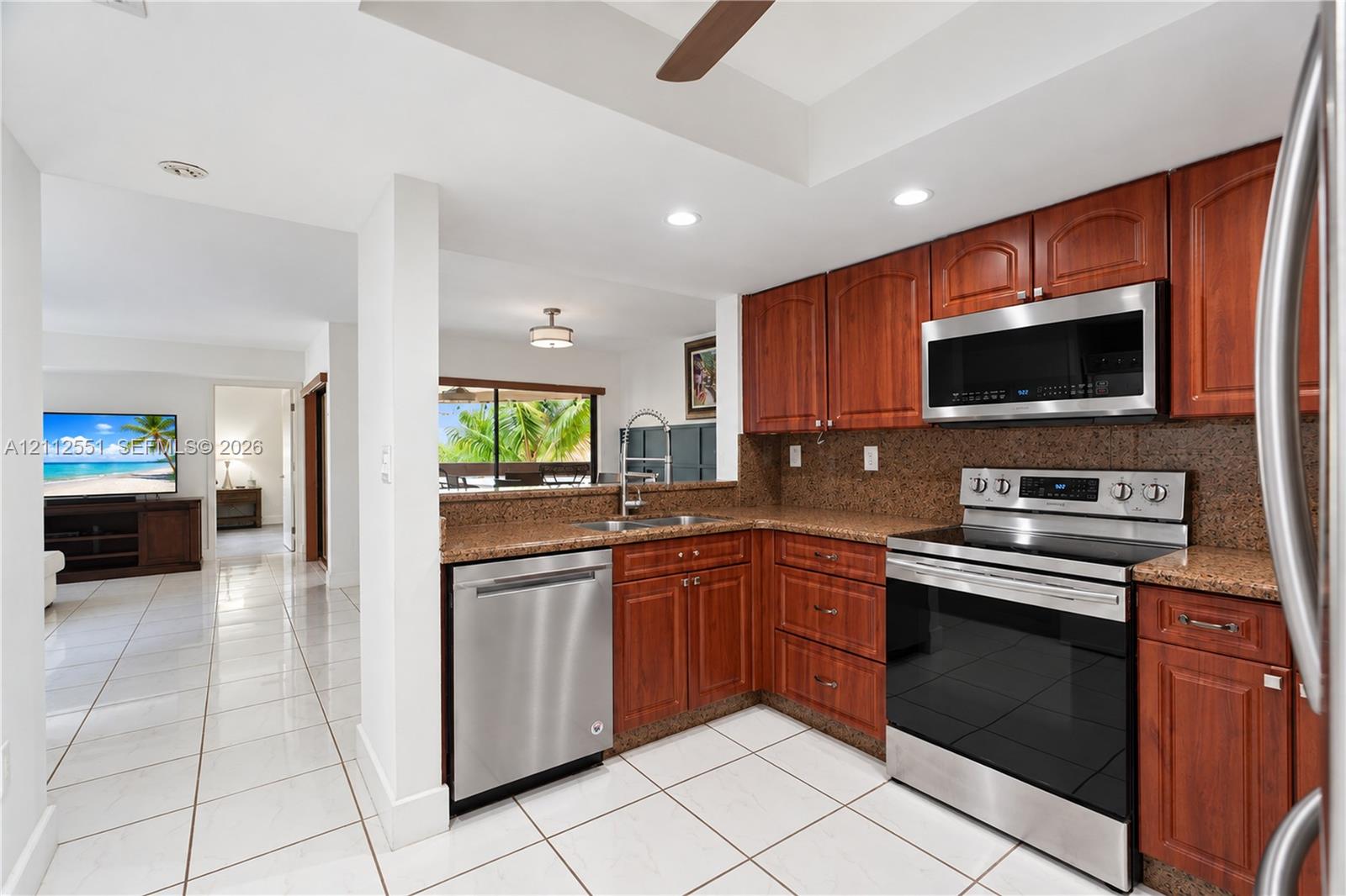 Kitchen featuring cherry-finish cabinetry, stone-texture countertops, stainless steel appliances, and tile flooring Kitchen featuring cherry-finish cabinetry, stone-texture countertops, stainless steel appliances, and tile flooring