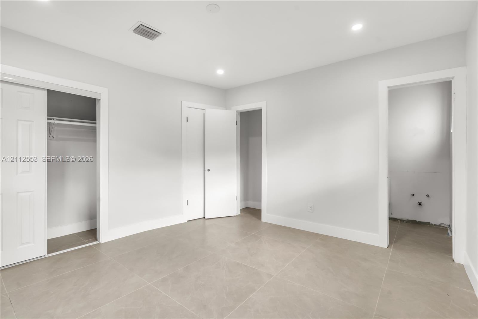 Neutral-toned ceramic tile flooring, recessed ceiling lighting, and multiple interior closets with white paneled doors