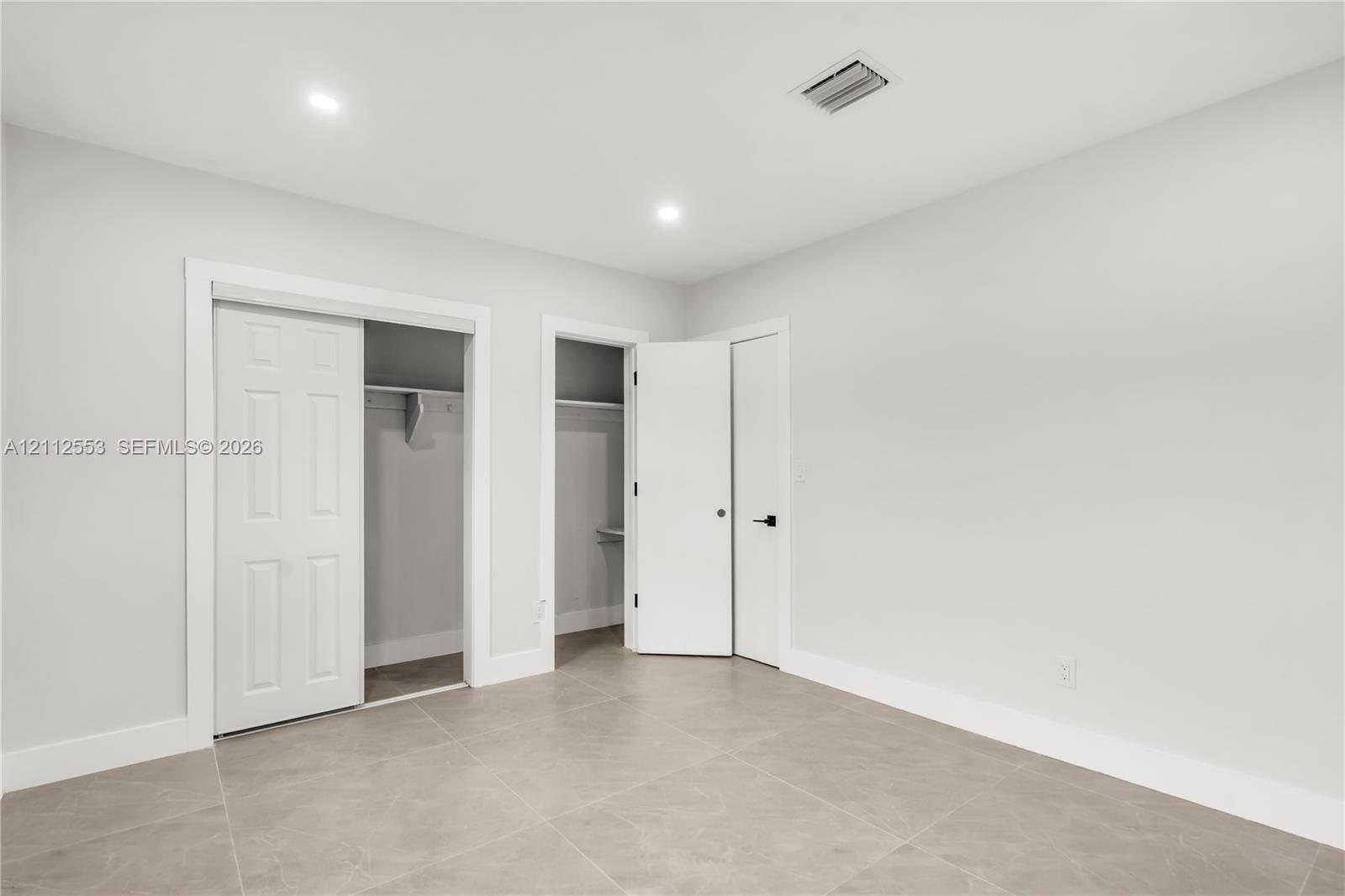 Neutral-toned tile flooring, recessed ceiling lighting, two reach-in closets, and solid-core doors with matte black hardware