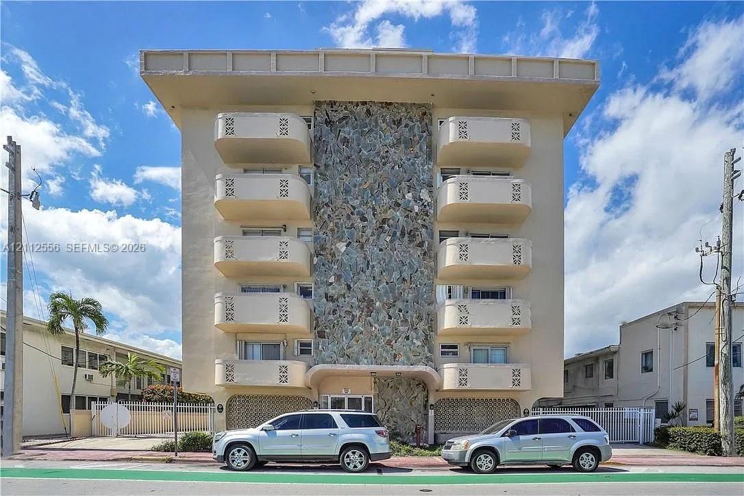 Mid-century modern architectural facade featuring a central stone-clad vertical accent, cantilevered balconies with geometric patterned railings, and a distinct horizontal roofline