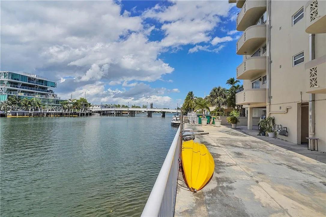 Waterfront concrete patio featuring a metal railing, multi-level balconies, and direct water access