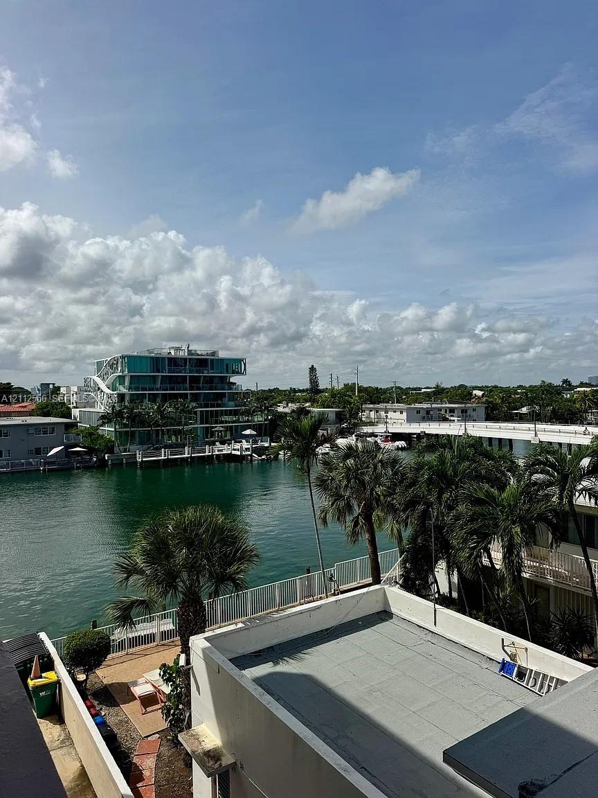 Waterfront property featuring a canal, palm trees, and structural hardscaping