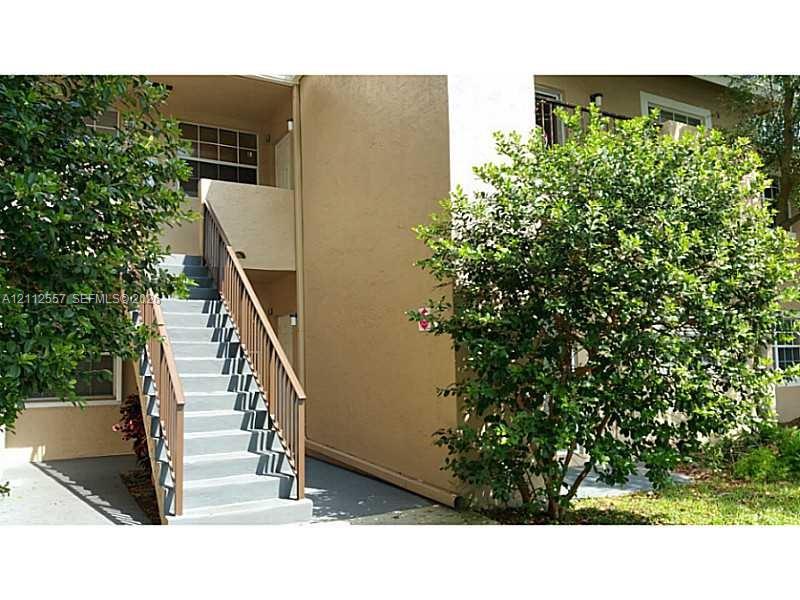 Exterior staircase with wooden railings featuring concrete steps and stucco siding