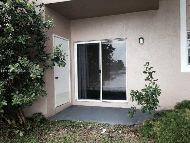 Exterior patio area featuring a concrete base, sliding glass door, private exterior storage closet, and wall-mounted sconce lighting