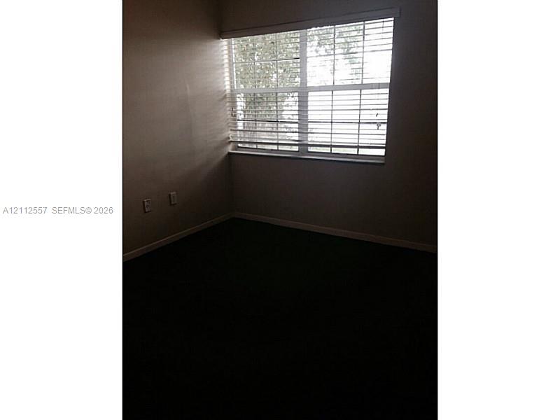 Room featuring wall-to-wall carpeting and a multi-pane window with horizontal blinds