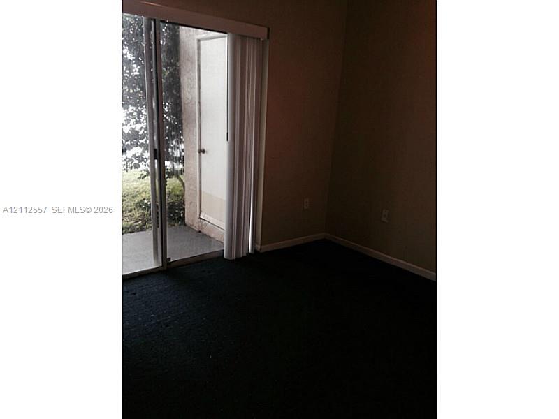 Sliding glass door with vertical blinds opening to a concrete patio