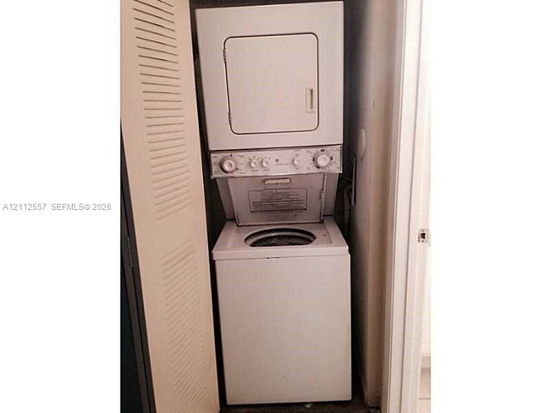 Stacked laundry center featuring a top-loading washer, front-loading dryer, and louvered closet door