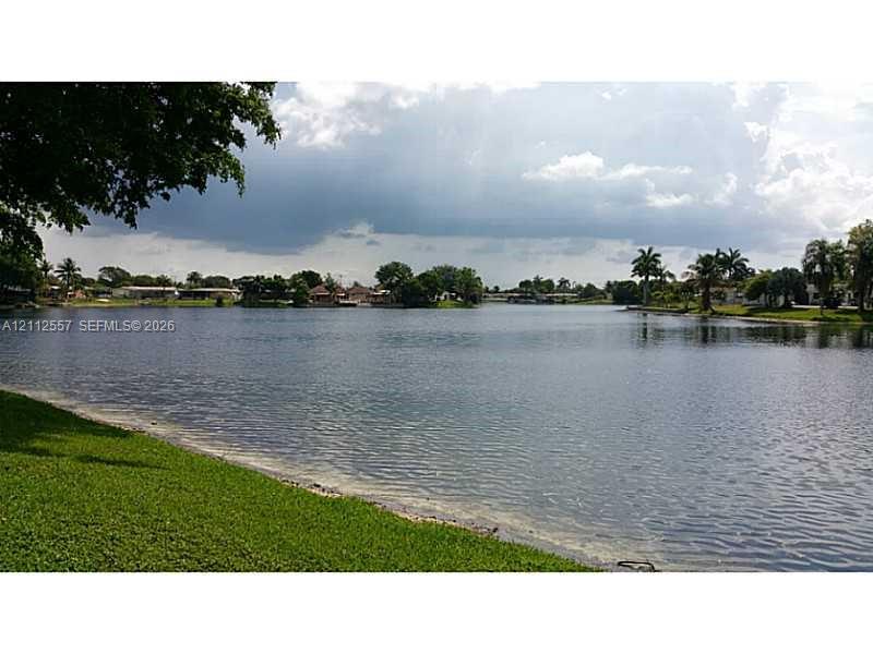 Waterfront property featuring a grassed shoreline and mature palm trees