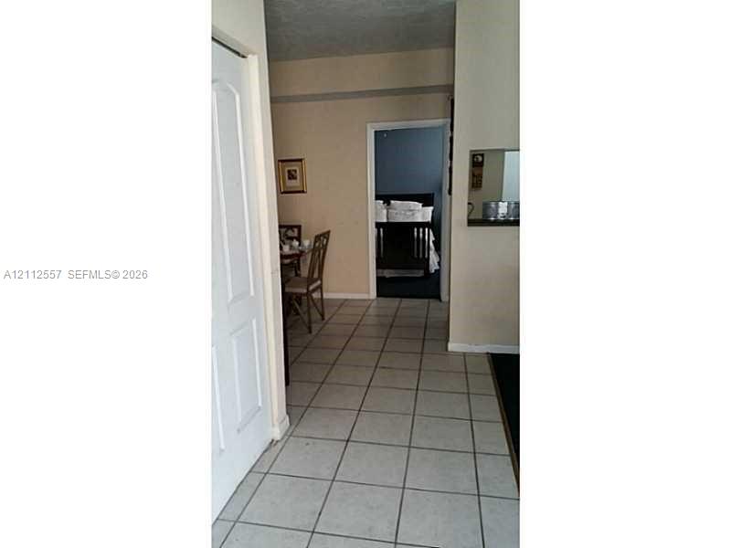 Neutral-toned interior featuring ceramic tile flooring, a recessed wall-mounted mirror, and a multi-panel door