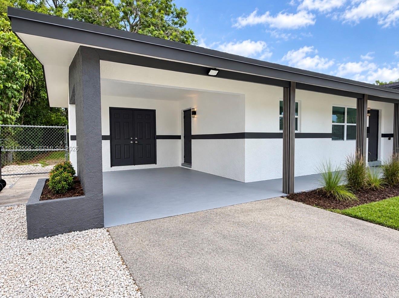 Modern exterior featuring a covered carport with painted concrete flooring, double entry doors, a built-in masonry planter, and recessed lighting Modern exterior featuring a covered carport with painted concrete flooring, double entry doors, a built-in masonry planter, and recessed lighting