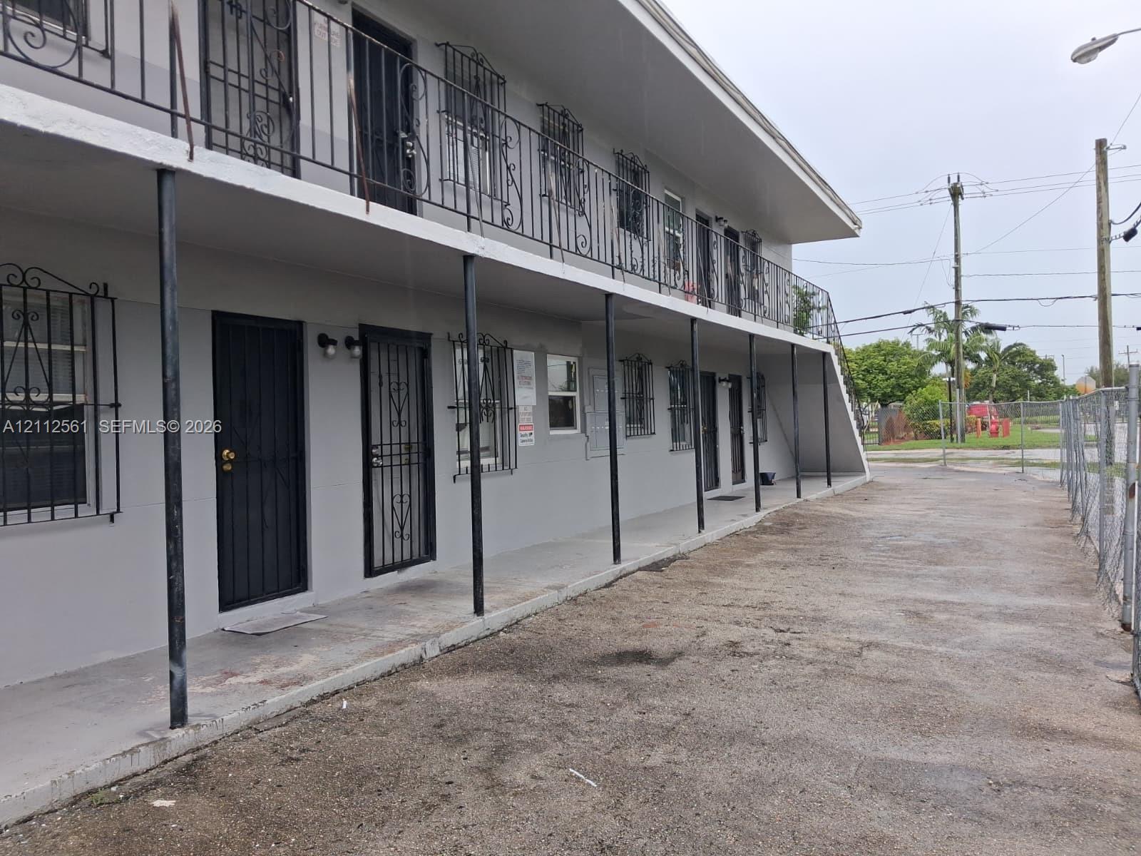 Two-story exterior featuring a concrete facade, metal railings, decorative metal window security bars, and covered porches