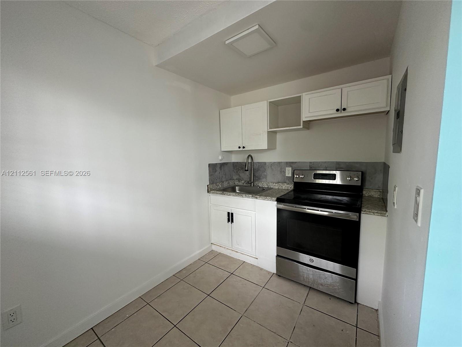Kitchen featuring white cabinetry, stone-finish countertops, stainless steel range, gooseneck faucet, and tiled flooring