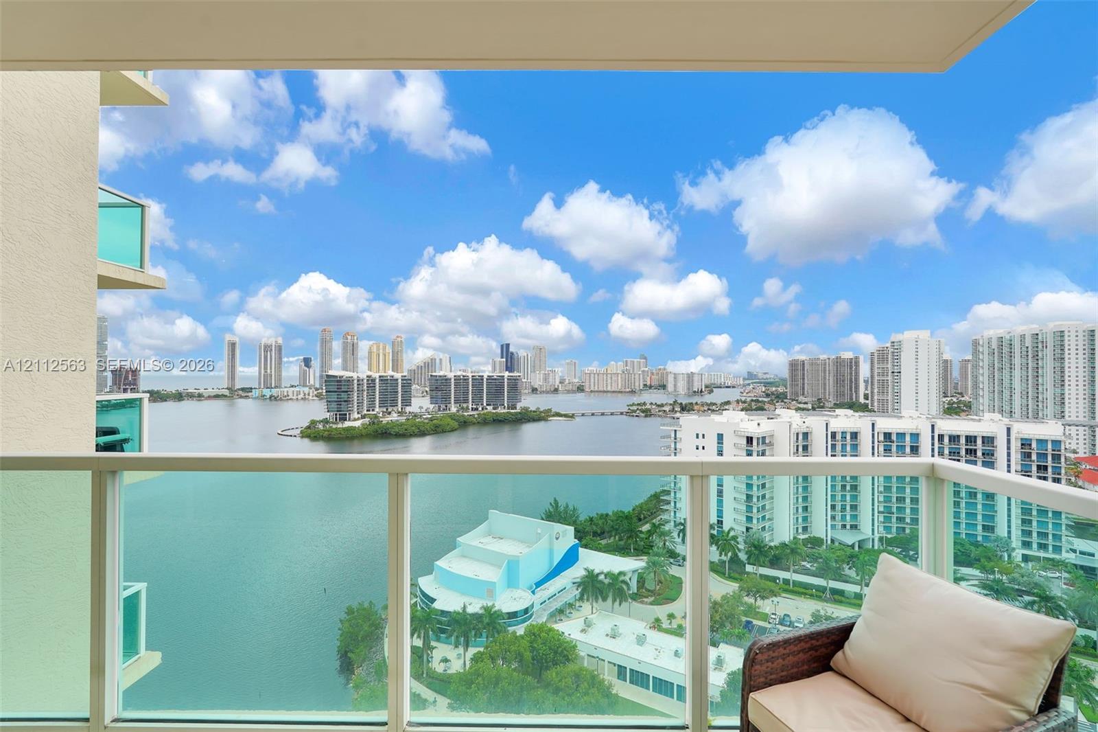Private balcony featuring glass panel railing and panoramic waterfront and city skyline scenery