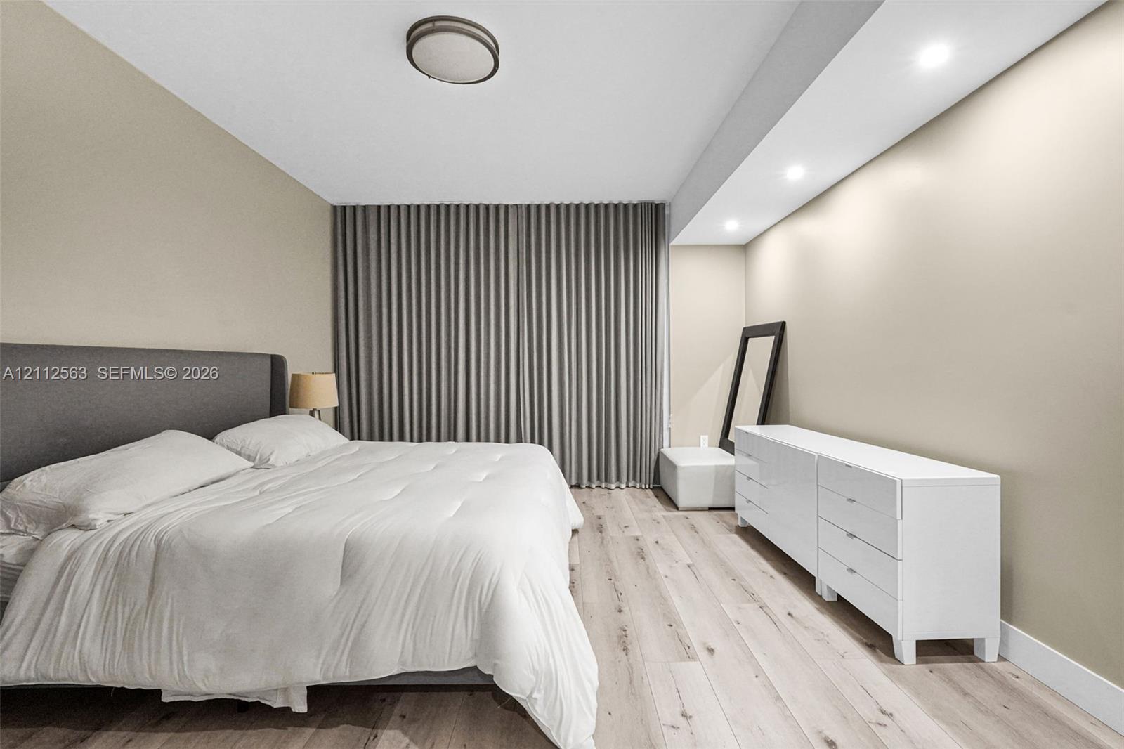 Light-toned wood-finish flooring, recessed ceiling lighting, and floor-to-ceiling drapery