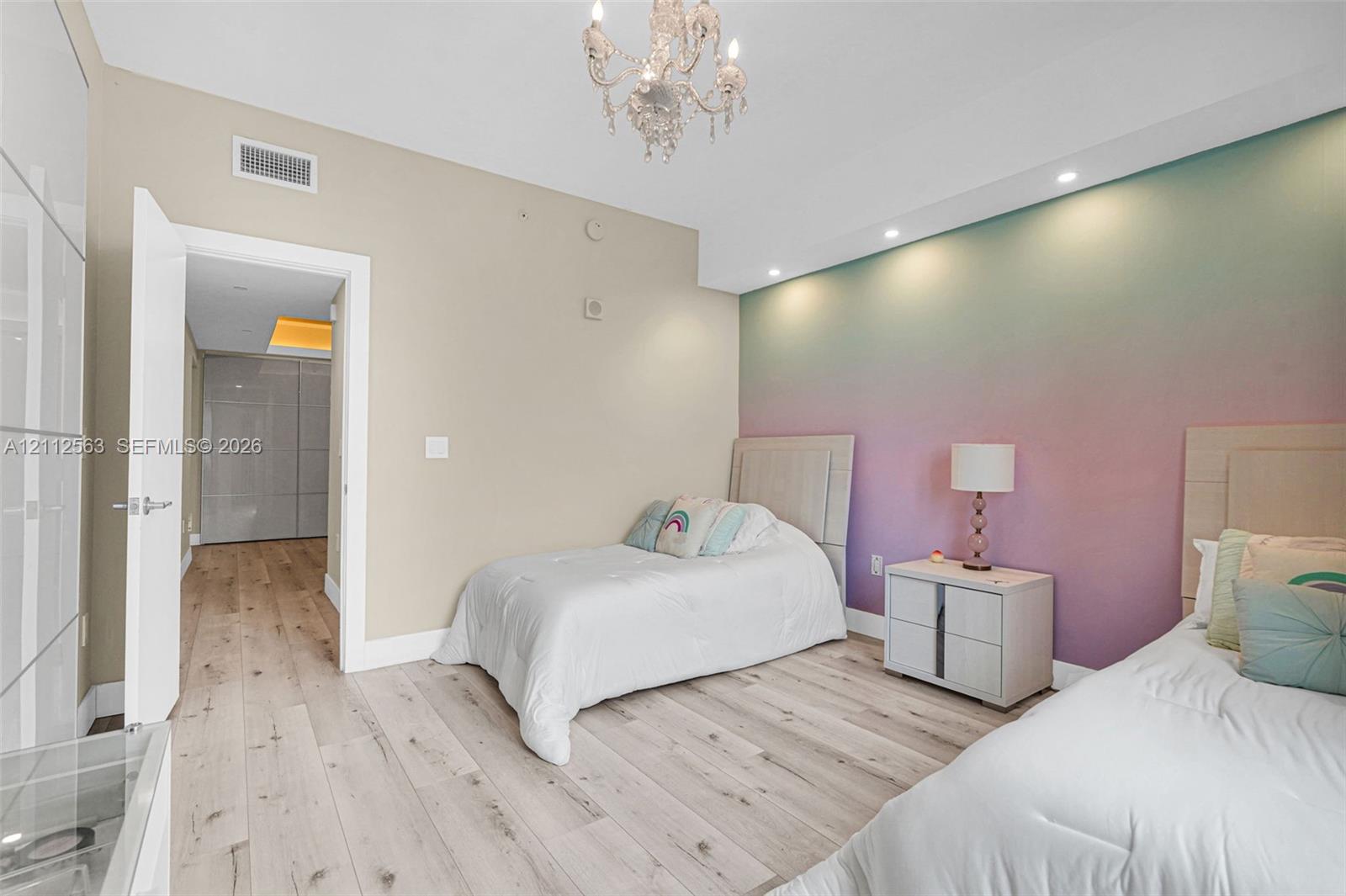 Wood-finish flooring, recessed ceiling lighting, decorative chandelier, and floor-to-ceiling built-in cabinetry