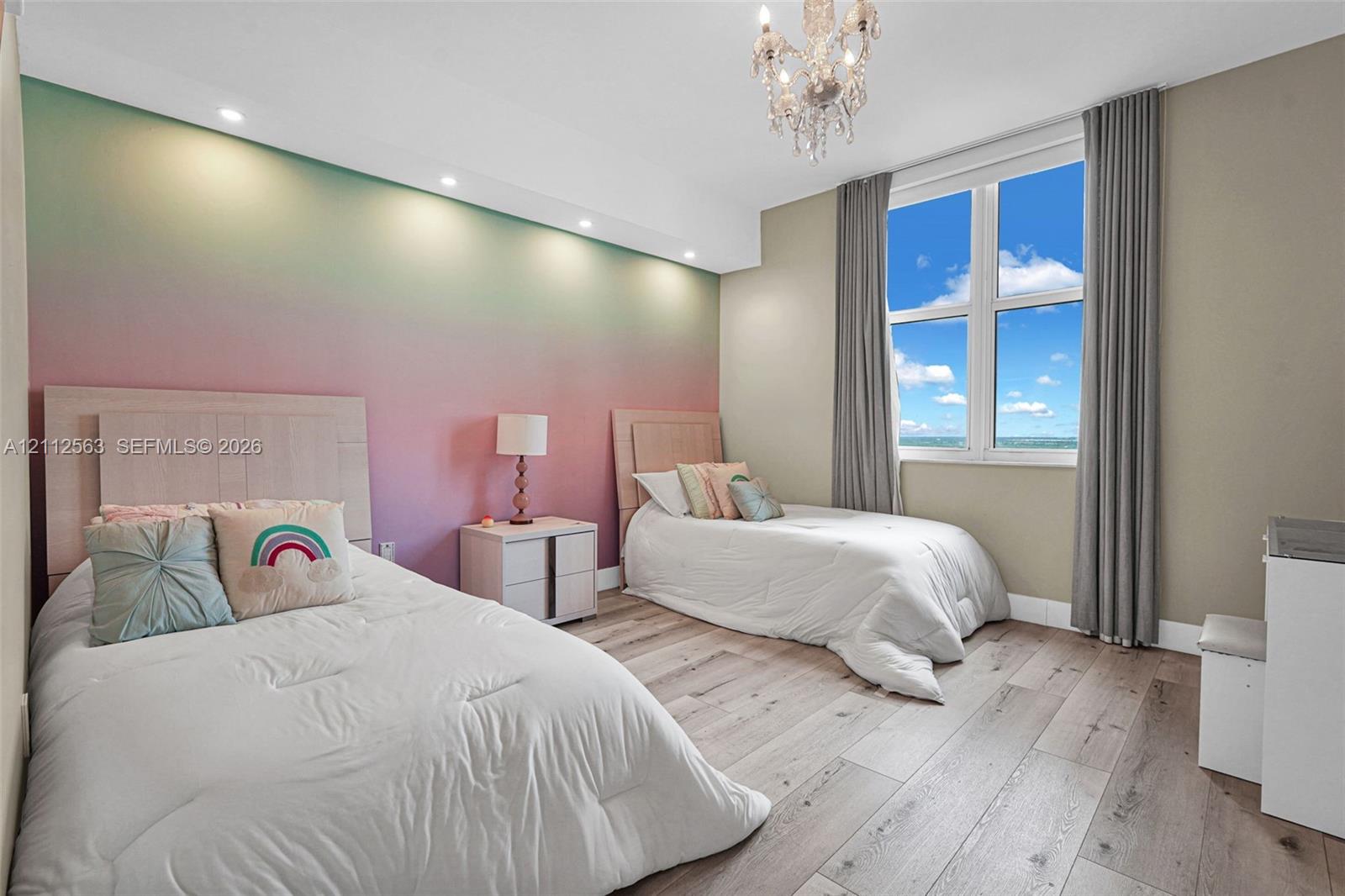 Wood-finish flooring, recessed ceiling lighting, a decorative crystal chandelier, and large windows with prominent skyward exposure
