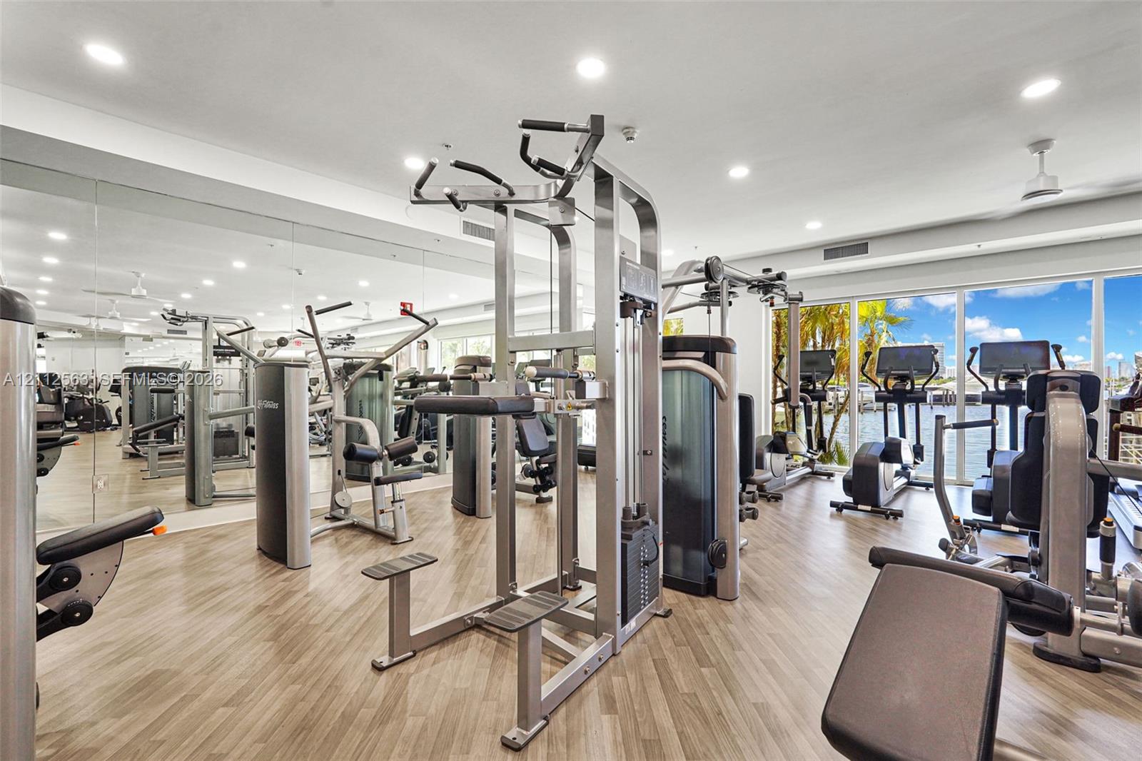 Fitness facility featuring full-wall mirrors, wood-finish flooring, recessed lighting, and floor-to-ceiling windows