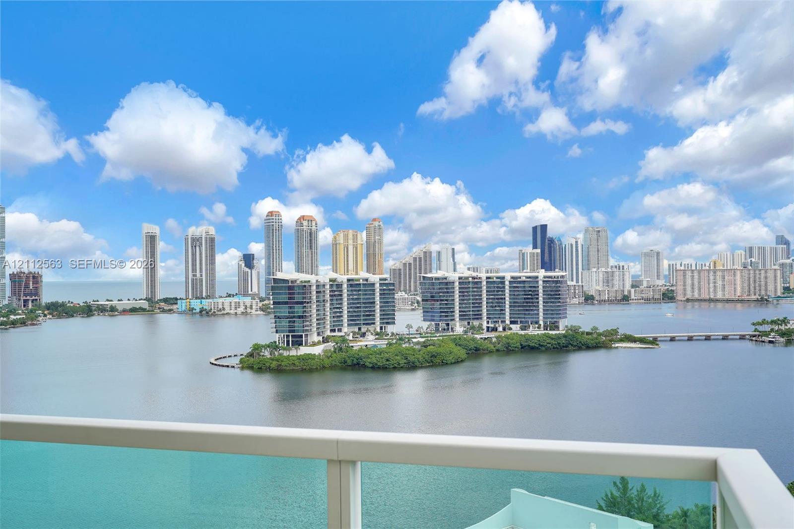 Balcony featuring a glass panel railing and panoramic waterfront and city skyline scenery
