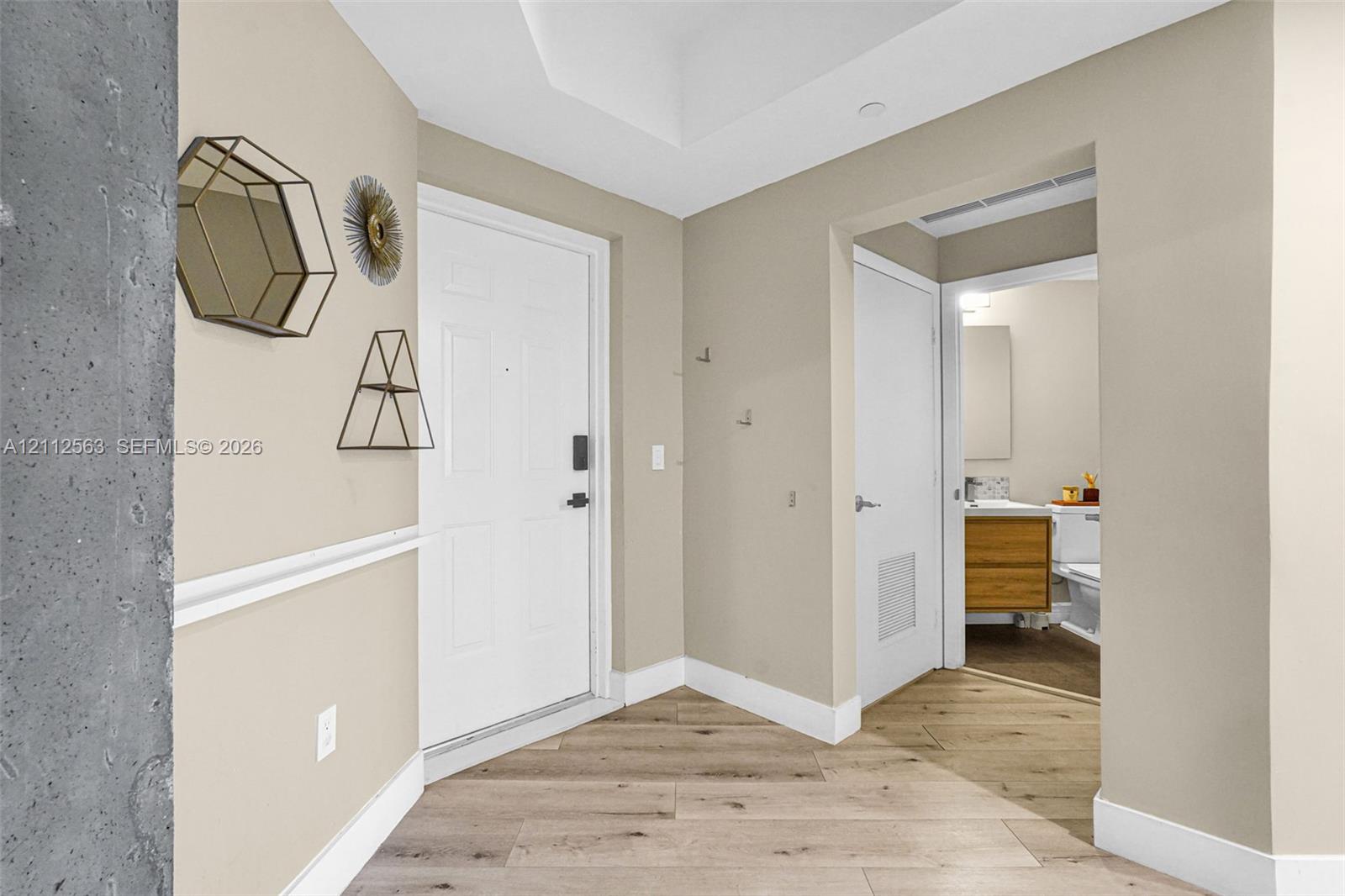 Entryway featuring wood-finish flooring, white paneled door with electronic deadbolt, recessed ceiling lighting, and chair rail molding