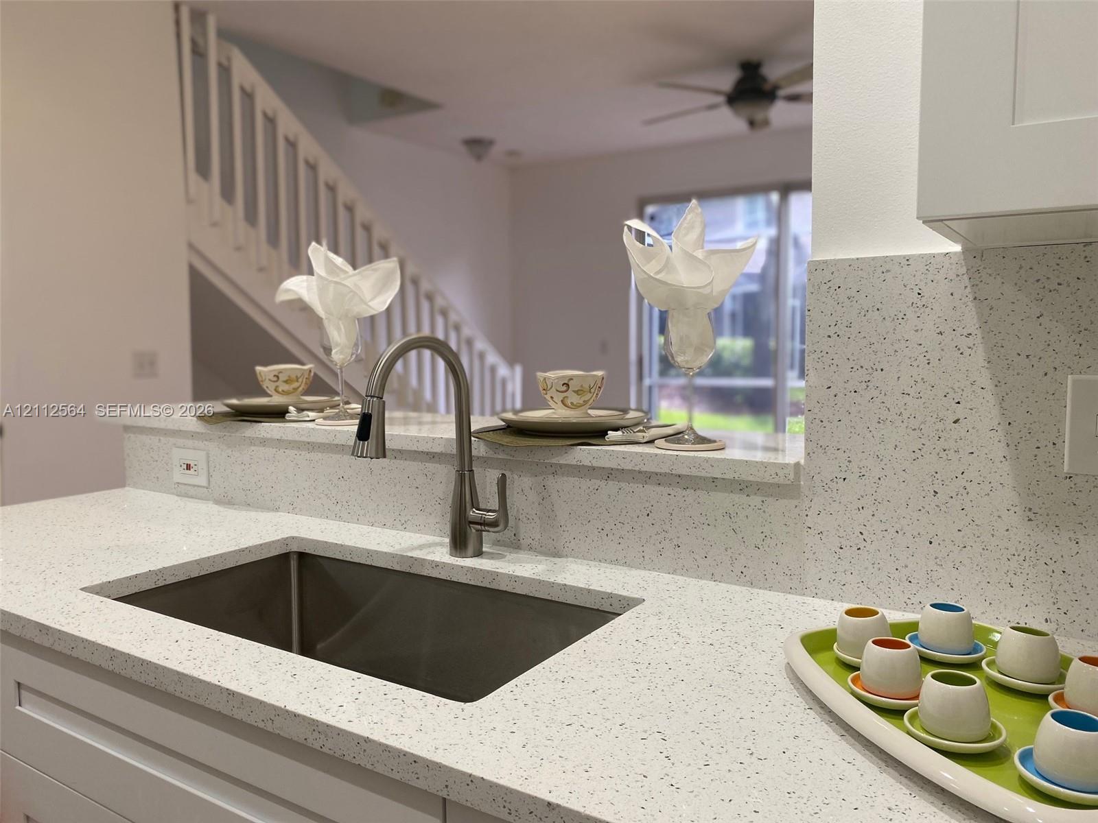 Kitchen featuring speckled quartz countertops, an undermount stainless steel sink, and a high-arc pull-down faucet