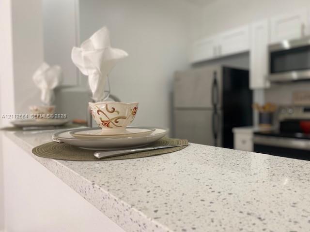 Kitchen featuring a speckled stone-finish countertop, white cabinetry, and stainless steel appliances