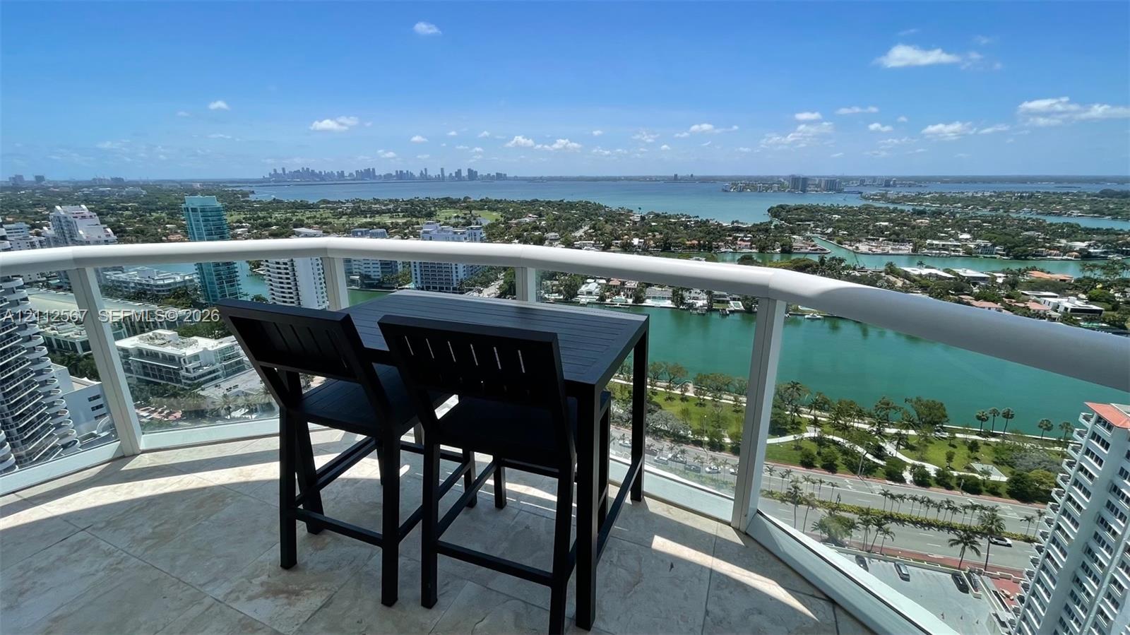 Covered balcony featuring stone tile flooring and a curved white railing