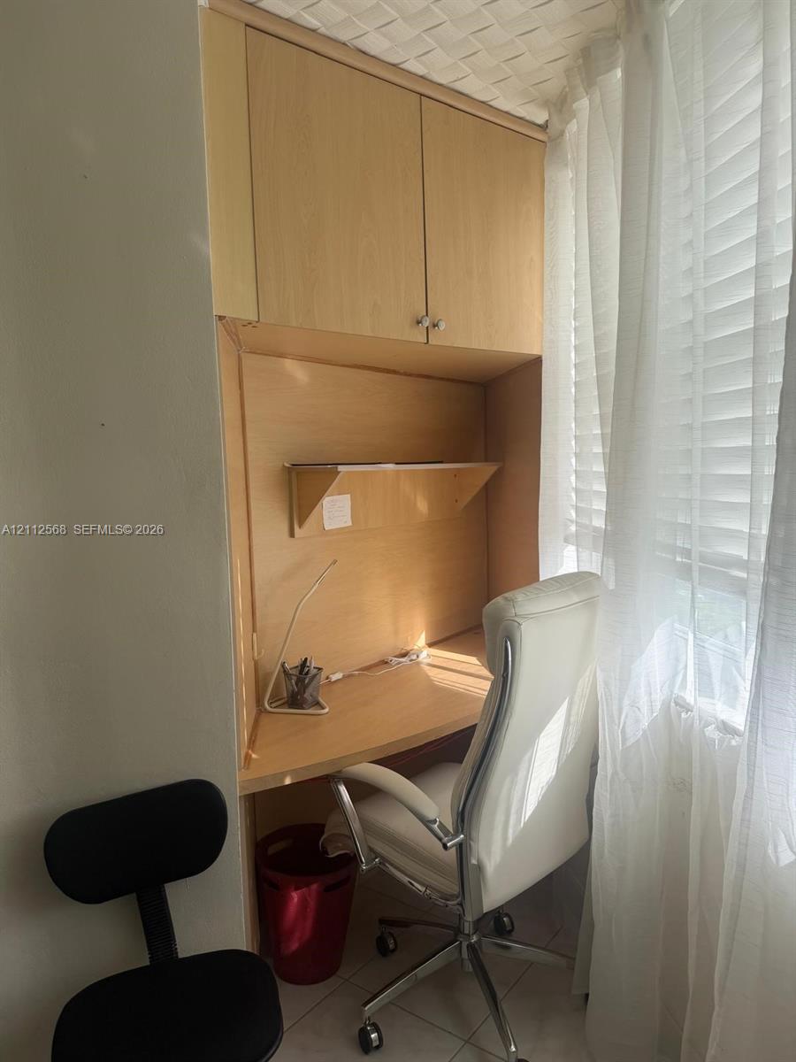 Built-in wood-finish cabinetry featuring an integrated desk surface, overhead storage, and a fixed wall-mounted shelf