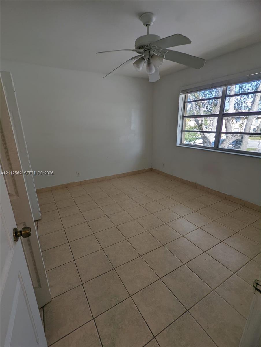 Neutral-toned ceramic tile flooring, ceiling fan with integrated lighting, and multi-pane window