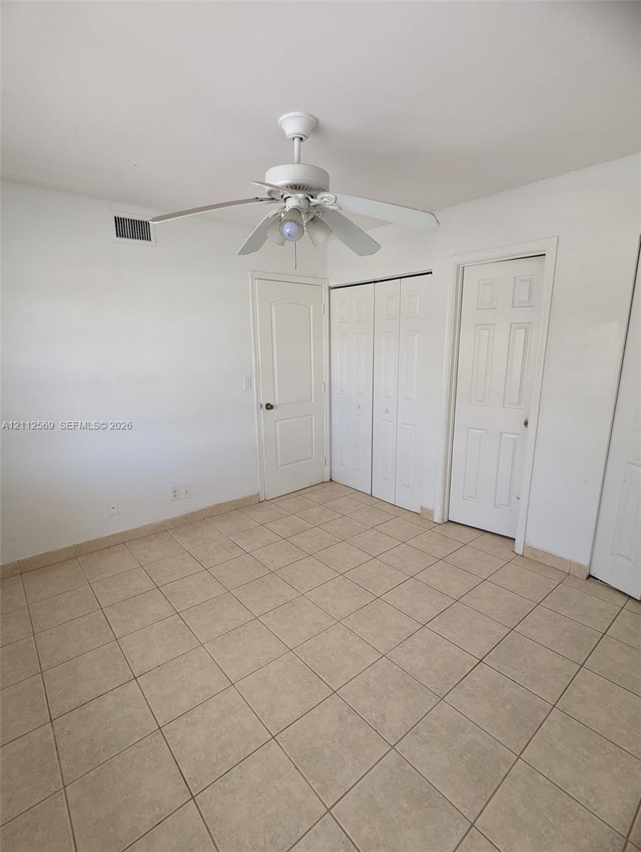Ceramic tile flooring, white six-panel interior doors, and a ceiling fan with integrated lighting