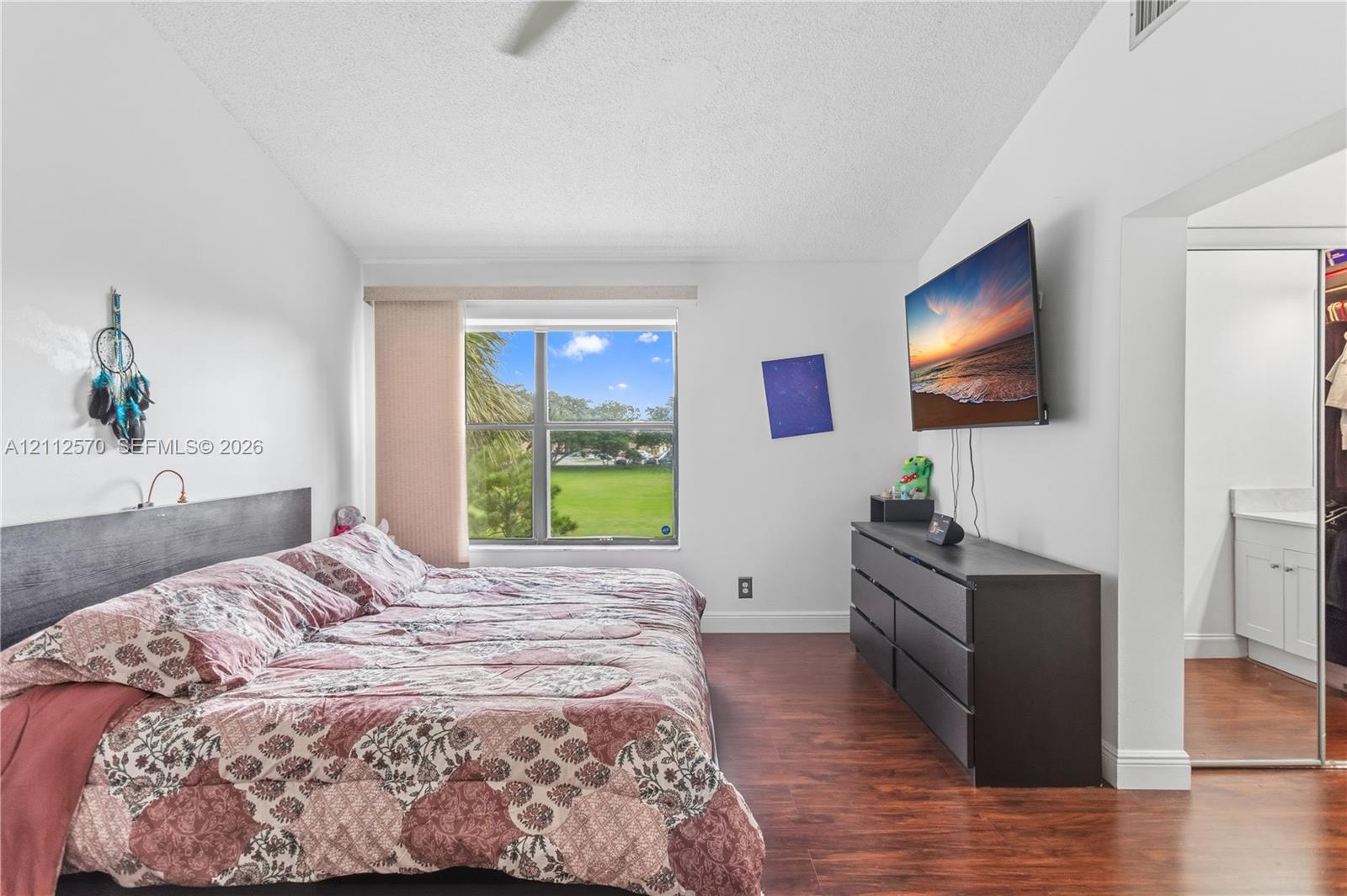 Wood-finish flooring, vaulted ceilings, and a window with exterior scenery
