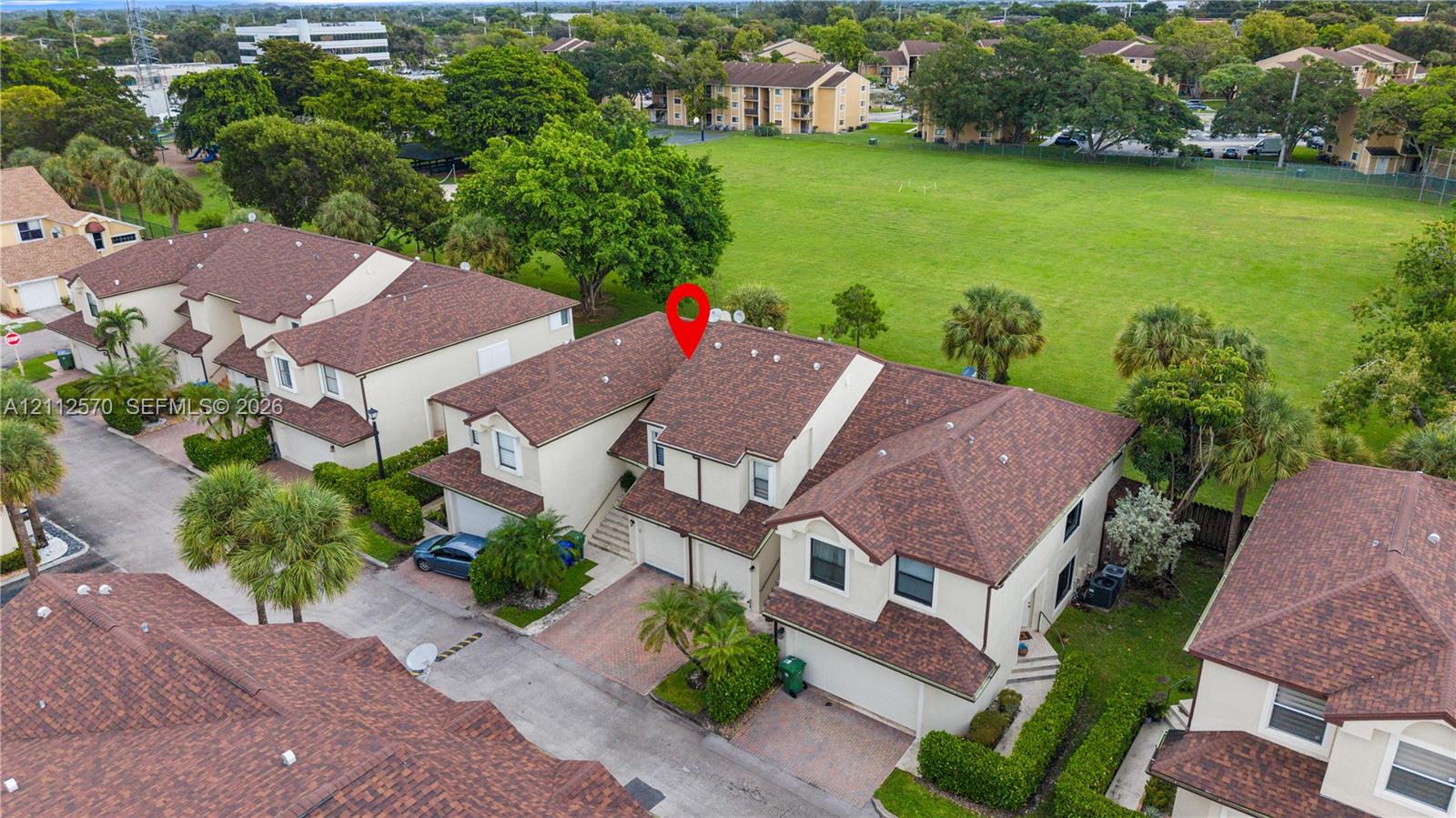 Multi-story residential exterior featuring a multi-gabled shingled roof, stucco facade, and paver driveway