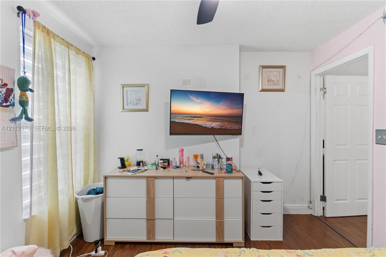 Wood-finish flooring, white paneled interior door, and ceiling fan fixture