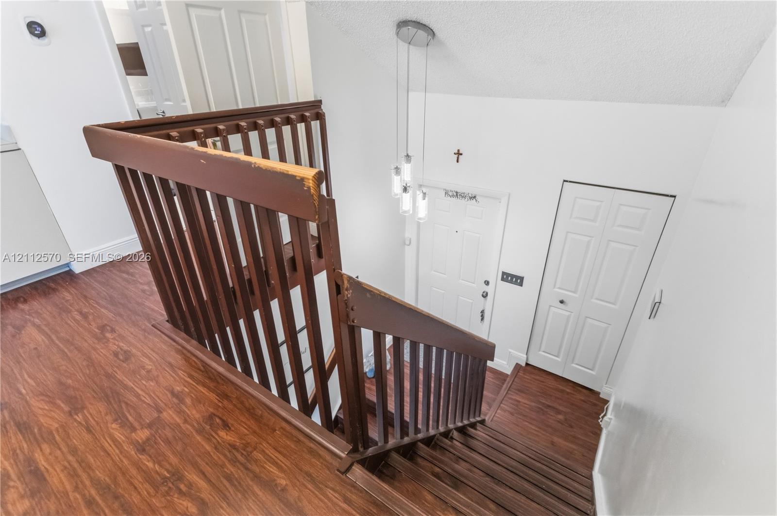 Staircase featuring a wooden banister, wood-finish flooring, and a multi-pendant light fixture