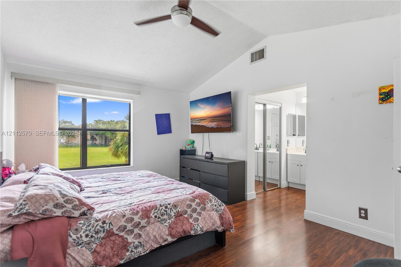 Vaulted ceiling featuring a ceiling fan, wood-finish flooring, and a large window