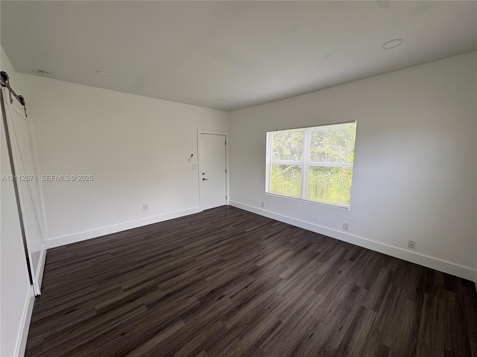Interior space featuring wood-finish flooring, recessed lighting, and a white sliding barn door