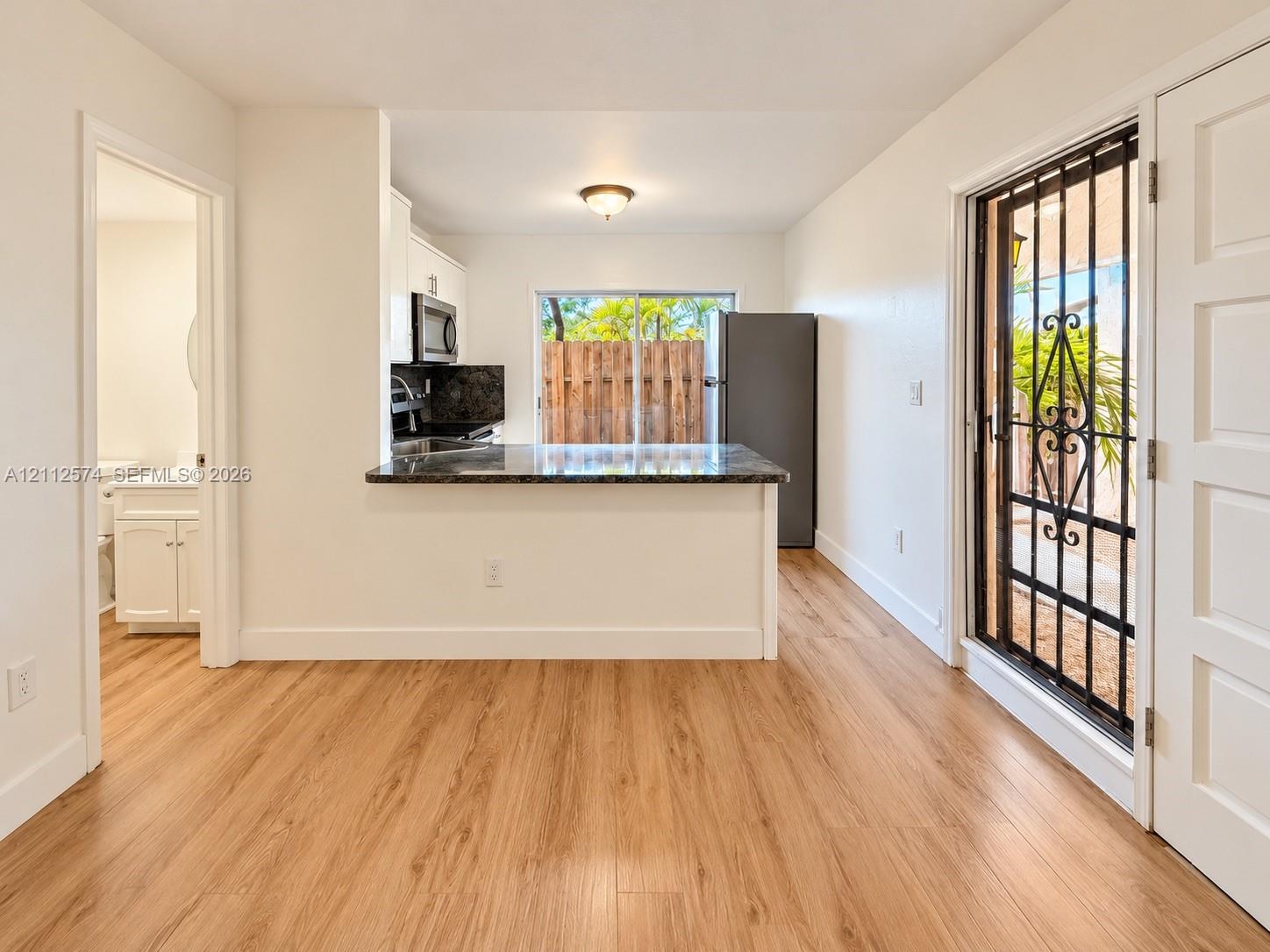 Kitchen featuring wood-finish flooring, stone-surfaced peninsula, and built-in cabinetry, including an exterior metal security door