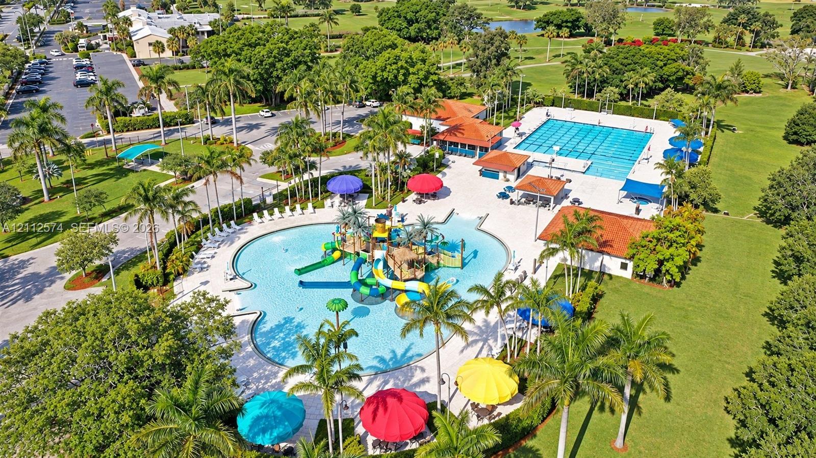 Recreational complex featuring a large swimming pool, lap pool, multi-level water slides, water play structures, and tile-roofed pavilions